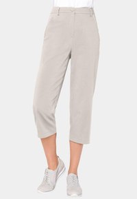 Pantalons cropped beiges clairs en tissu doux avec une texture lisse, dotés d'une fermeture à un bouton et de poches latérales.