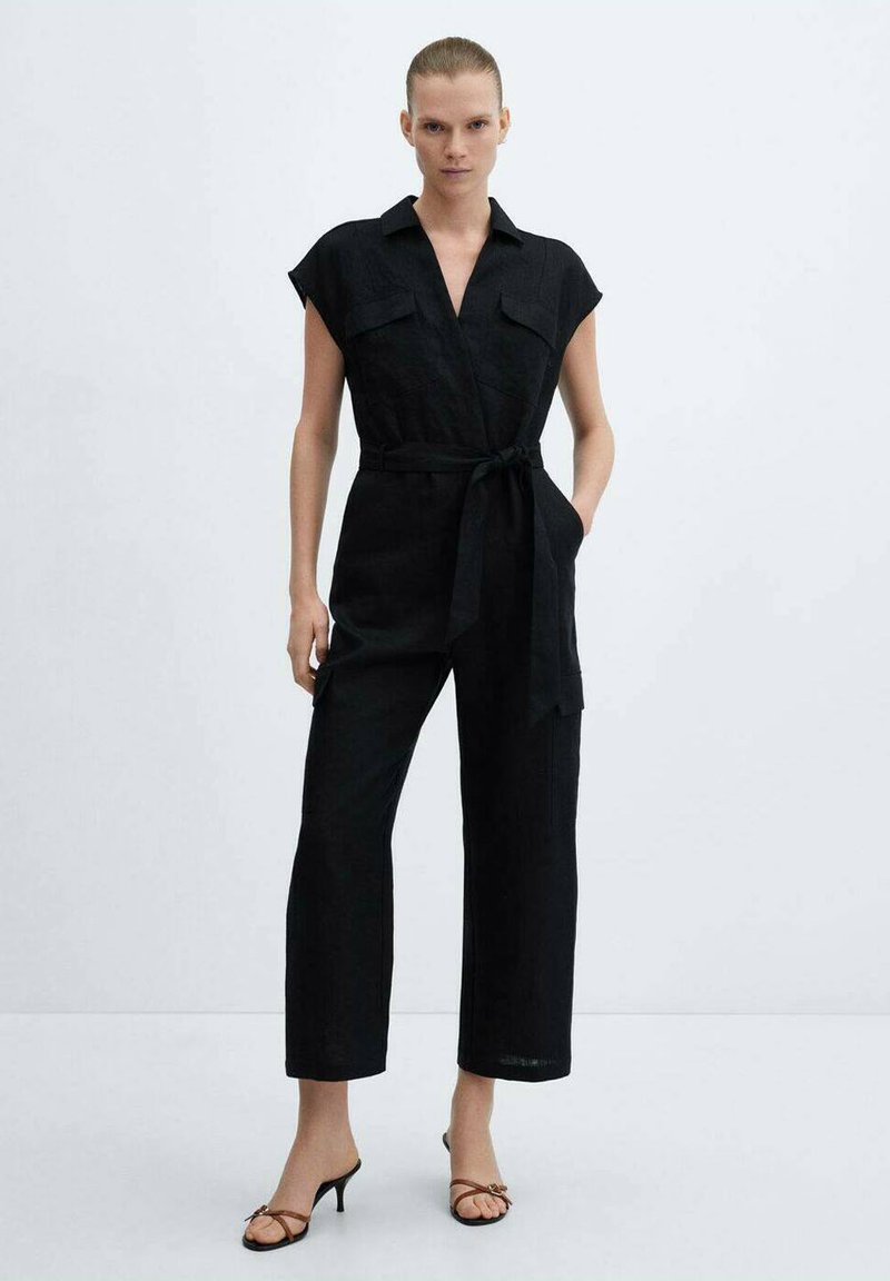 Zwart linnen jumpsuit met korte mouwen, kraag en riem. Voorzien van twee frontzakken en een ontspannen pasvorm met wijde benen.