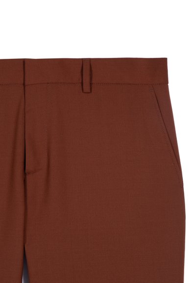 Brune bukser med lige pasform, flad front, to sidelommer og en subtil struktur. Bæltestropper og pæne syning detaljer ved taljen.