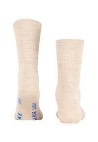 Meias bege de malha com textura canelada, apresentando letras azuis nas solas. As meias têm comprimento padrão até a canela e material macio.