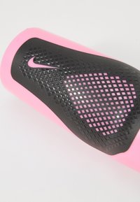 Nike sportuitrusting met een roze siliconen grip en een getextureerd zwart rubberen deel met een ruitpatroon en een klein logo.