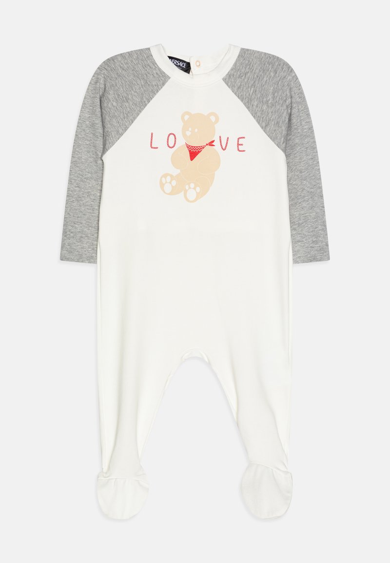 Macacão branco com mangas raglan cinzentas. Apresenta um gráfico de um urso e o texto "AMOR" em vermelho. Os pés têm punhos arredondados. Material de algodão macio.