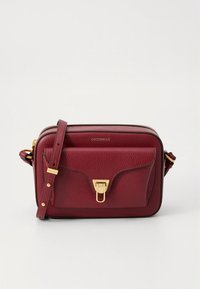 Μπορντό δερμάτινη τσάντα χιαστί με υφή, εξαρτήματα σε χρυσό τόνο, κλείσιμο με φερμουάρ και μπροστινή τσέπη με κούμπωμα. Ρυθμιζόμενο λουράκι.