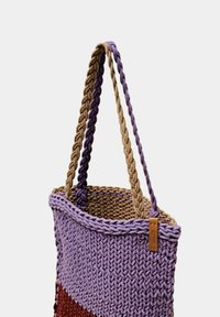 Gevlochten draagtas in paars en bruin, met gevlochten handvatten en een textuurrijk lichaam met een duidelijk horizontaal patroon.