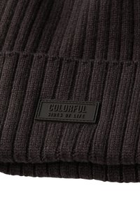 Gorro de canalé gris oscuro con un patrón de tejido texturizado y una etiqueta rectangular negra que dice "LADOS COLORIDOS DE LA VIDA."