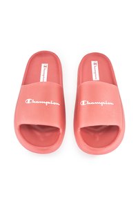 Pink rubber slide sandals with open toes and a wide strap featuring the "Champion" logo in white. Smooth texture and rounded edges.