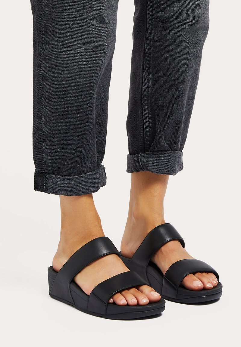 Zwarte spitzen sandalen met twee brede banden van glad leer. De zool is iets verhoogd met een gestructureerde afwerking.