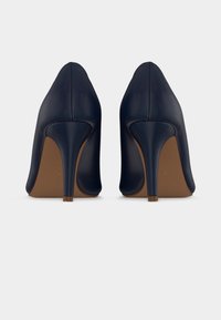 Μπλε ναυτικό δερμάτινα παπούτσια με ψηλό τακούνι, με μυτερό σχέδιο στη μύτη και κομψή σιλουέτα. Τα τακούνια είναι λεπτά και στενεύουν σε στρογγυλεμένη άκρη.