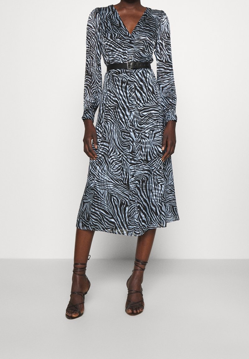 Zebramönstrad klänning i blått och svart tyg, med v-ringning, lång ärm och midjebälte. Texturerad finish och medellång längd.
