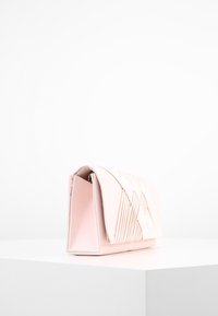 Różowa skórzana kopertówka z żeberkowym wzorem, z klapą na zawiasie i sztywną formą. Gładka tekstura, kompaktowy rozmiar.