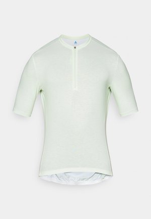 Svijetlozelena kratka majica s kratkim rukavima, visokim ovratnikom, zatvaranjem na pola zatvarača i prilagođenim krojem. Ima glatku tkaninu s blagom teksturom.