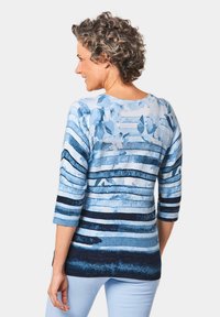 Blauer, gemusterter Pullover mit horizontalen Streifen in verschiedenen Blautönen. Weicher Strickstoff mit Rundhalsausschnitt und Dreiviertelärmeln.