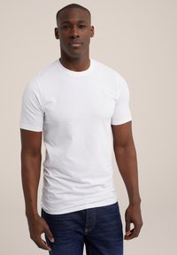 Camiseta blanca de manga corta hecha de algodón, con un escote redondo. Combinada con jeans de color azul oscuro, que tienen una textura suave y un corte clásico.