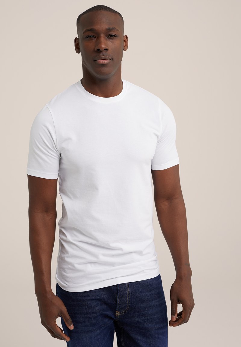 Camiseta blanca de manga corta hecha de algodón, con un escote redondo. Combinada con jeans de color azul oscuro, que tienen una textura suave y un corte clásico.