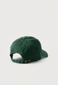 Πράσινο βαμβακερό καπέλο του μπέιζμπολ με καμπυλωτό γείσο, ρυθμιζόμενο λουράκι στο πίσω μέρος και ραμμένες τρύπες εξαερισμού στην κορυφή.