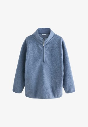 Gaišzils flīsa pulvers ar augstu apkakli, pus-ciparu un teksturētu virsmu. Tam ir garas piedurknes un brīva griezuma siluets.