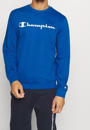 Modrá bavlněná mikina s bílým logem "Champion", kulatým výstřihem a žebrovanými manžetami a lemem. Nositelná s tmavými kalhotami.