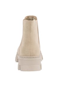 Bottines en suede beige avec une semelle blanche épaisse, présentant des coutures texturées et une finition lisse, vues de l'arrière.