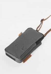 Gray, zippered pouch made of smooth material with a brown leather strap and tag. Features embossed logo on the front. Compact rectangular shape.