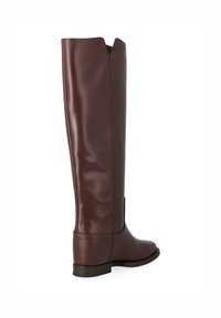 Bottes en cuir bordeaux hautes avec une finition lisse, présentant un détail découpé en haut, un talon bas empilé et des coutures renforcées.