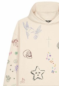 Sweat à capuche beige avec des esquisses colorées comprenant deux colibris, un crâne aux yeux en forme de cœur, une étoile avec un visage, un ange, des planètes et divers petits symboles.