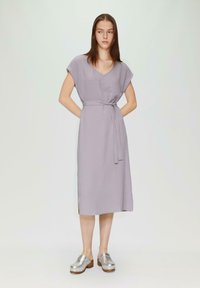 Lavendel Midi-Kleid aus strukturiertem Stoff mit V.Ausschnitt und kurzen Ärmeln, tailliert mit einem passenden Gürtel. Kombiniert mit silbernen Clogs.