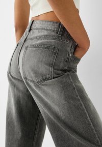 Grå denimjeans med avslappnad passform, medelhög midja och framfickor. Tyget har en något strukturerad yta.