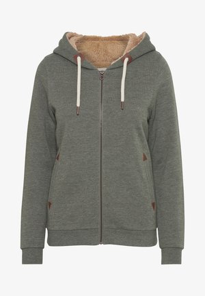 Olívazöld kapucnis, cipzáras pulóver, puha bézs bolyhos béléssel, krémszínű zsinórokkal és barna bőrkiegészítőkkel.