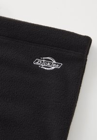 Fekete bolyhos anyag, finom textúrával, fehér hímzett "Dickies" logóval. Látható varrásokkal az éleken.