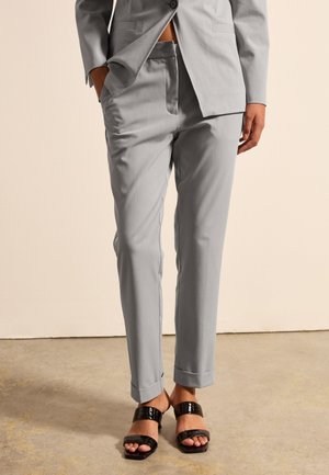 Light gray tailored pants made of smooth fabric, featuring a straight leg design and cuffed hems, paired with glossy black sandals.