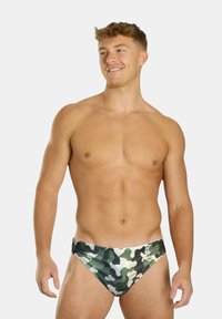 Herren-Schwimmslips in einem grünen Camouflage-Muster. Hergestellt aus leichtem, dehnbarem Material mit einem niedrigen Schnitt und einer glatten Oberfläche.