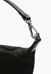 Sac en tissu noir avec une texture lisse, doté d'une bandoulière en cuir et d'un clip mousqueton en métal, présentant une ouverture zippée.