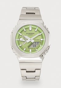 Relógio G-Shock com bracelete em aço inoxidável prateado, mostrador analógico-digital verde e características iluminadas; resistente à água até 20 bar.