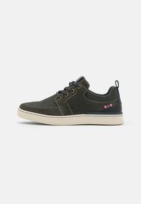 Olive green sneakers with a textured fabric upper, contrasting navy accents, round laces, and a beige rubber sole featuring stitched details.