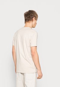 Beige cotton T-shirt with a crew neck and short sleeves, featuring a plain design and a relaxed fit. Back view is shown.