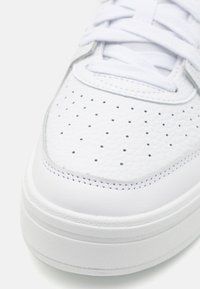 Valge nahk Sneakers perforeritud ülemise, lapiku nöörimise ja pehme kraega. Paks valge tald tekstuuriga viimistlusega. Minimalistlik disain.