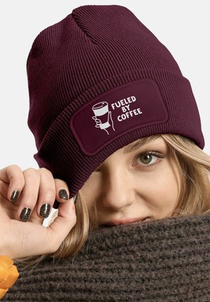 Maroon knit beanie with a textured pattern. Features a white patch stating "FUELED BY COFFEE" with a graphic of a coffee cup.