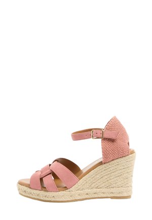 Sandale compensée en suède rose avec talon tressé, bride à la cheville et bout ouvert, vue de profil sur fond blanc.