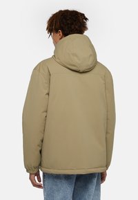 Khaki isolerad jacka med huva, med en mjuk textur, elastiska ärmslut och en lös passform, sedd bakifrån.
