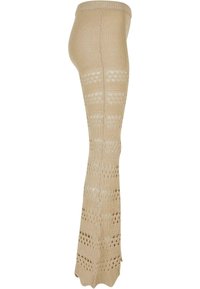 Pantalon beige en maille avec jambes larges, présentant des rayures horizontales alternées pleines et ajourées, ainsi qu'un ourlet festonné.