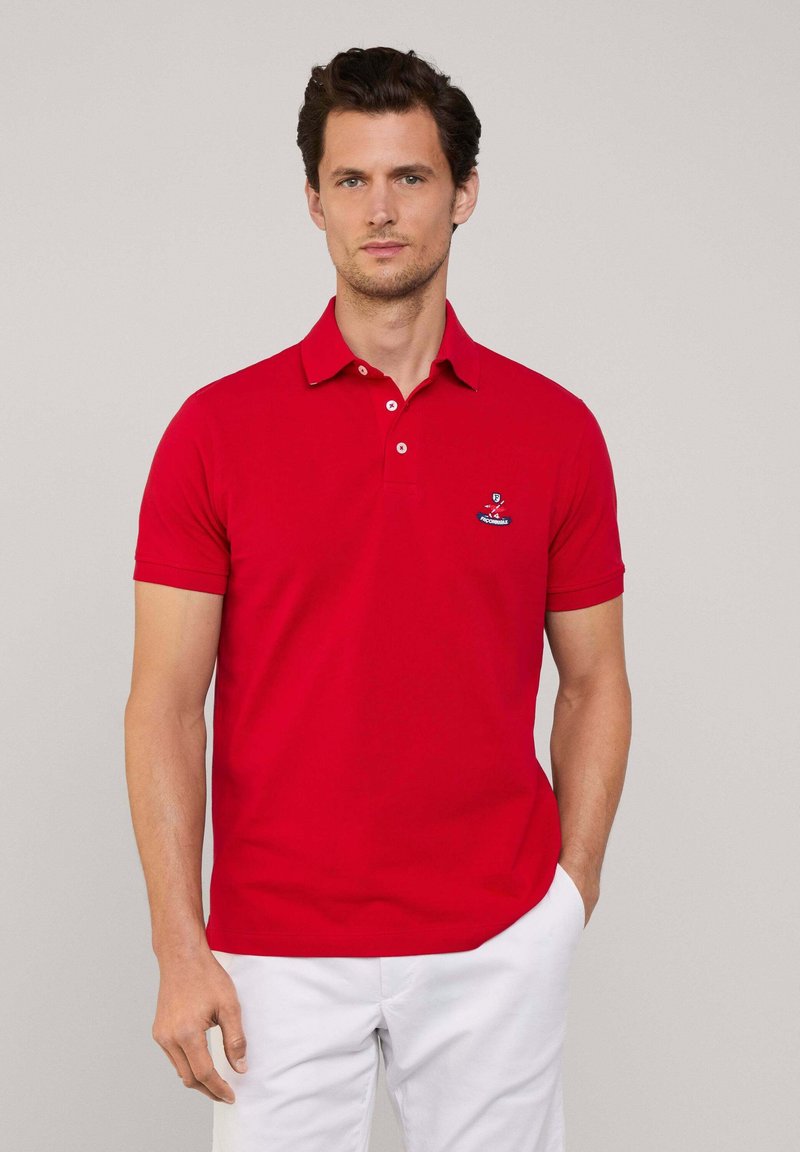 Polo shirt rossa con colletto, maniche corte e due bottoni. Presenta un logo ricamato sulla parte sinistra del petto. Tessuto in cotone liscio.