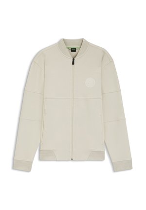 Hellbeige Jacke mit Reißverschluss aus weichem Stoff, mit rundem Logo auf der Brust, gerippten Bündchen und einem strukturierten Design mit Einsätzen.