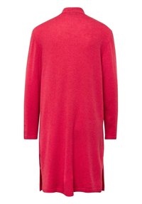 Vêtement long à manches rouges en matériau tricot doux, avec un col et des fentes sur les côtés pour faciliter le mouvement.