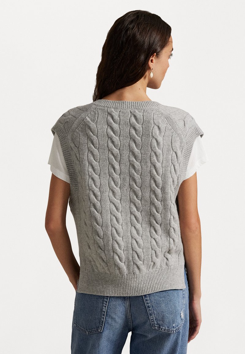 Grå strikvest med kabelmønster, korte ærmer, ribbestrikket kant og rund halsudskæring, båret over en hvid t-shirt.