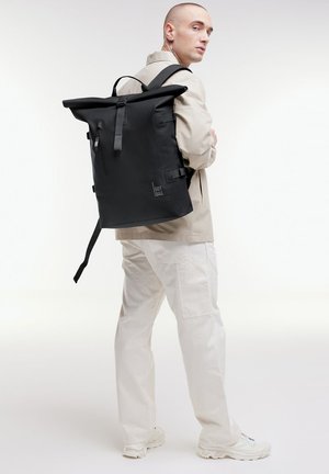 Zaino nero a roll-top con spallacci regolabili, design elegante e tasca frontale con zip. Realizzato in materiale resistente, presenta dettagli con logo.