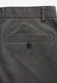 Un pantalon gris foncé présentant une texture lisse, une poche arrière boutonnée et des passants de ceinture, mettant en avant un design simple et fonctionnel.