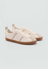 Sneakers color crema con una texture liscia, caratterizzati da dettagli color talpa, suola in gomma e lacci piatti. Design minimalista con perforazioni sui lati.