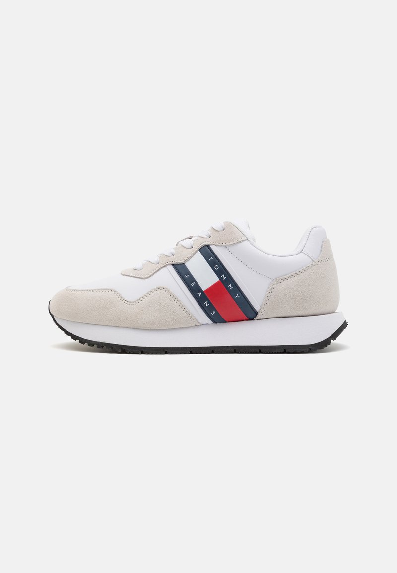Zapatillas hechas de cuero blanco y ante gris claro con una suela de goma negra. Presenta rayas horizontales rojas y marinas y la marca "TOMMY JEANS".