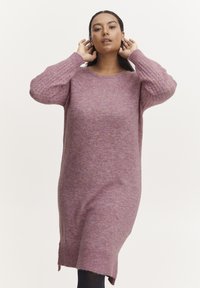 Abito maglione viola in maglia con maniche lunghe, scollatura rotonda e motivi a rilievo sulle maniche. Presenta spacco laterale per una maggiore libertà di movimento.