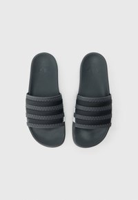 Čierne šľapky s tromi textúrovanými remienkami a hladkou stielkou. Na vrchu je vyrazené logo, s elegantným a minimalistickým dizajnom.